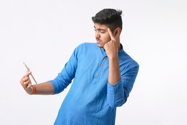Junger indischer Mann, der Smartphone verwendet und Ausdruck auf weißem Hintergrund gibt.