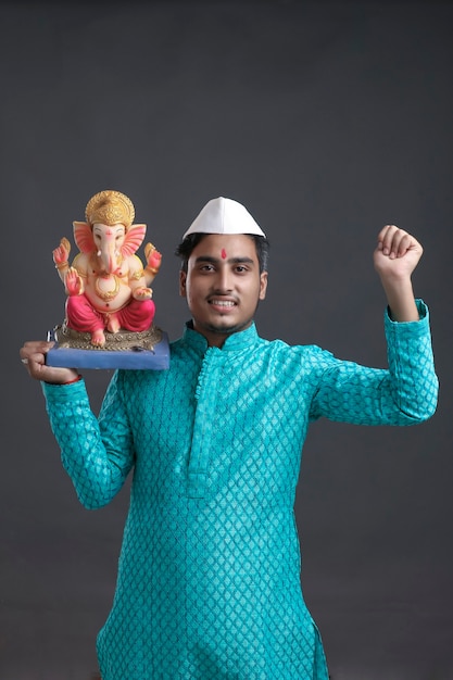 Junger indischer Mann mit Lord Ganesha Sclupture. das Ganesha-Fest feiern.