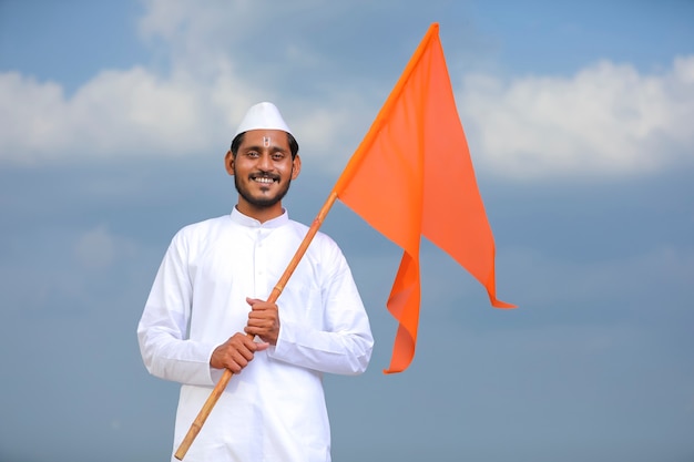 Junger indischer Mann (Pilger) in traditioneller Kleidung und wehende religiöse Flagge.