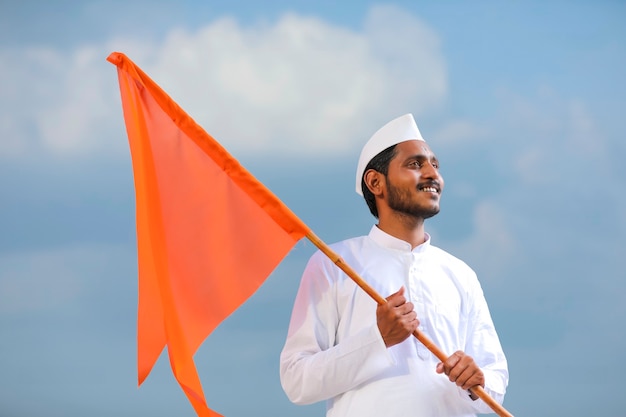 Junger indischer Mann (Pilger) in traditioneller Kleidung und wehende religiöse Flagge.