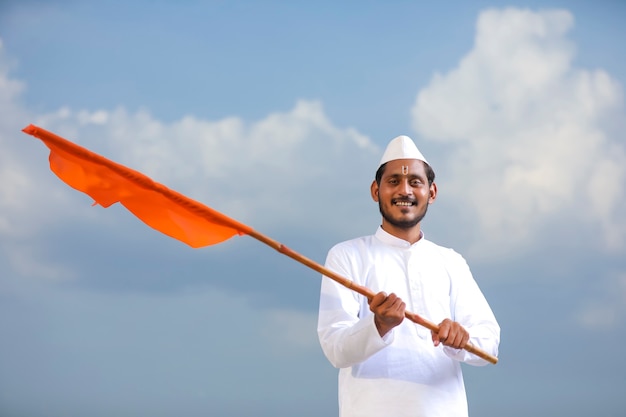 Junger indischer Mann (Pilger) in traditioneller Kleidung und wehende religiöse Flagge.