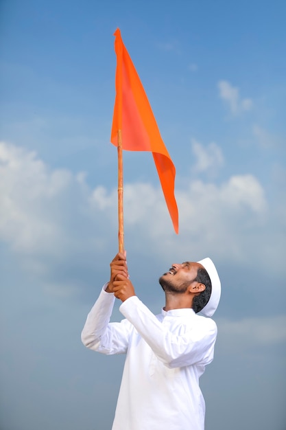 Junger indischer Mann (Pilger) in traditioneller Kleidung und wehende religiöse Flagge.