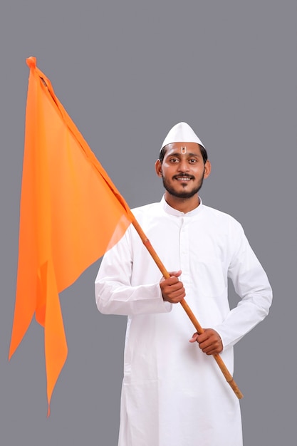 Junger indischer Mann (Pilger) in traditioneller Kleidung und wehende religiöse Flagge.
