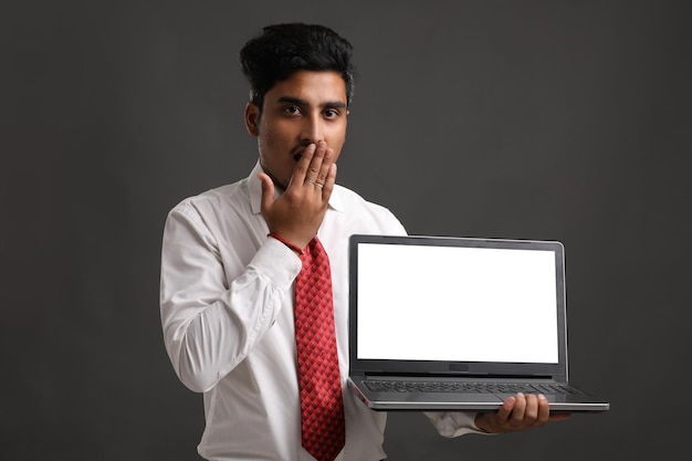 Foto junger indischer student, banker oder angestellter, der laptopbildschirm zeigt.