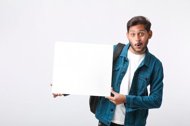 Junger indischer Student, der leeres Schild auf weißem Hintergrund zeigt.
