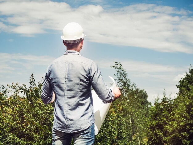 Junger Ingenieur mit Plänen im Park