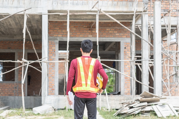 Foto junger ingenieur vor einem unfertigen haus.