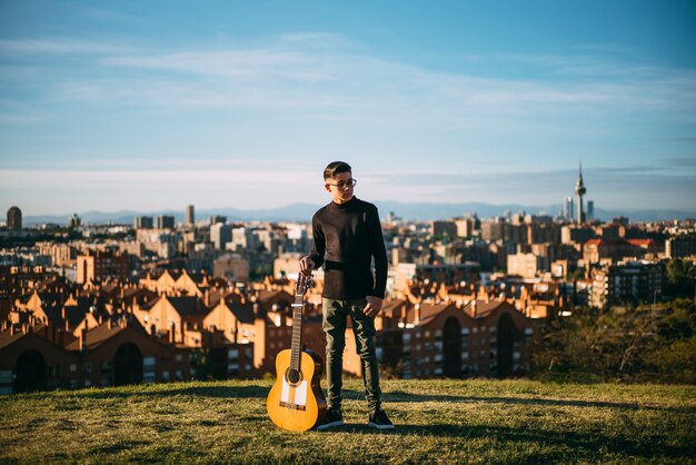 Junger Junge, der mit Gitarre in der Stadt von Madrid, Spanien aufwirft.