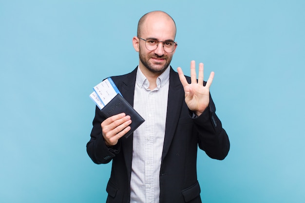 Junger kahlköpfiger Mann, der lächelt und freundlich aussieht, Nummer vier oder vierten mit der Hand nach vorne zeigend, Countdown