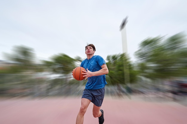 Junger kaukasischer Basketballspieler, der zu einem Dunk im Freien rennt