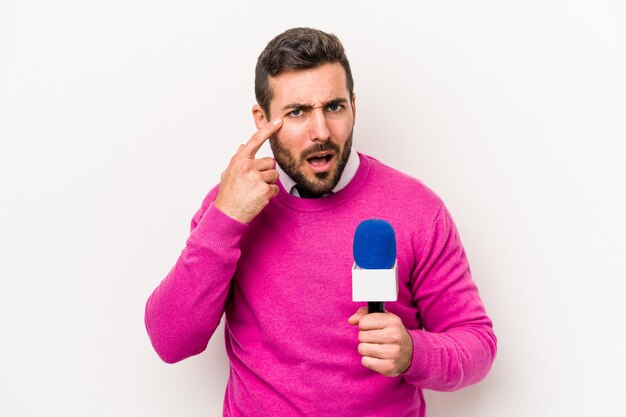 Junger kaukasischer Fernsehmoderator isoliert auf weißem Hintergrund, der eine Enttäuschungsgeste mit dem Zeigefinger zeigt