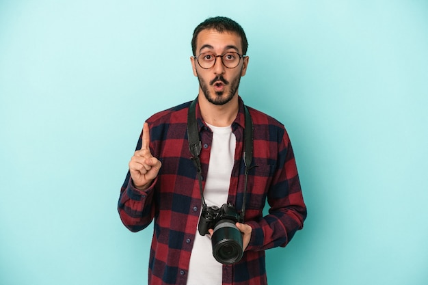 Junger kaukasischer Fotograf Mann isoliert auf blauem Hintergrund mit einer großartigen Idee, Konzept der Kreativität.