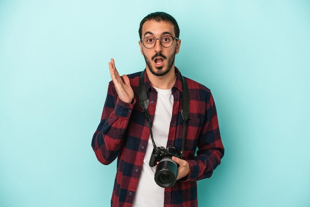 Junger kaukasischer Fotograf Mann isoliert auf blauem Hintergrund überrascht und schockiert