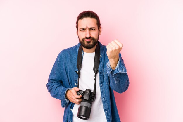 Junger kaukasischer Fotografmann, der Faust zur Kamera zeigt, aggressiver Gesichtsausdruck.