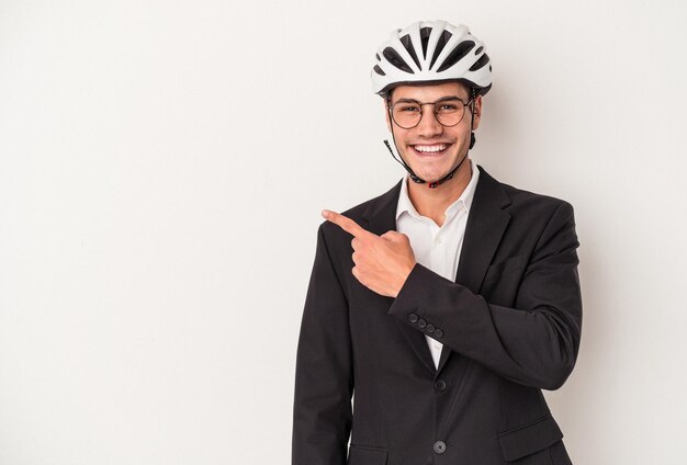 Junger kaukasischer Geschäftsmann mit Fahrradhelm isoliert auf weißem Hintergrund lächelnd und zur Seite zeigend, etwas auf Leerzeichen zeigend.