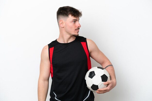 Junger kaukasischer gutaussehender Mann getrennt auf weißem Hintergrund mit Fußball