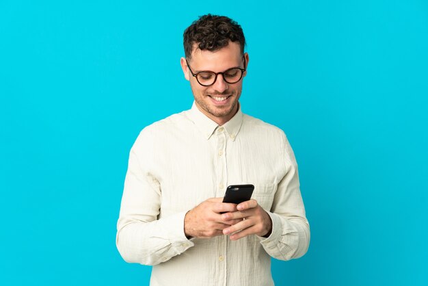 Junger kaukasischer gutaussehender Mann isolierte das Senden einer Nachricht mit dem Handy