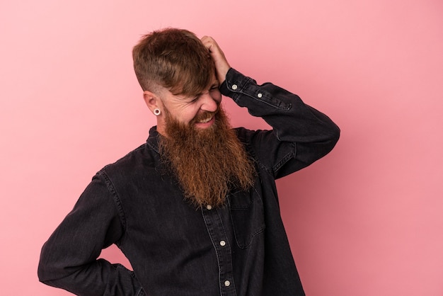 Junger kaukasischer Ingwermann mit langem Bart einzeln auf rosafarbenem Hintergrund, der Nackenschmerzen aufgrund von Stress hat, massiert und mit der Hand berührt.