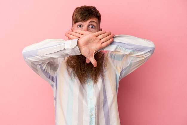 Junger kaukasischer Ingwermann mit langem Bart isoliert auf rosa Hintergrund, der eine Verweigerungsgeste macht