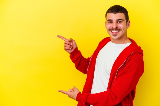 Junger kaukasischer kühler Mann lokalisiert auf gelber Wand aufgeregt mit Zeigefingern weg zeigend
