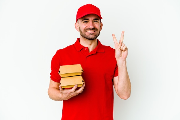 Junger kaukasischer Lieferbote lokalisiert auf weißem Hintergrund, der Nummer zwei mit den Fingern zeigt.