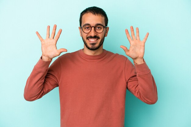 Junger kaukasischer Mann auf blauem Hintergrund isoliert, der Nummer zehn mit den Händen zeigt.