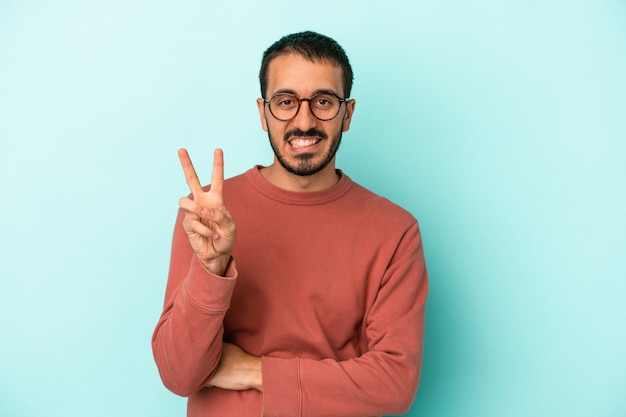 Junger kaukasischer Mann auf blauem Hintergrund isoliert, der Nummer zwei mit den Fingern zeigt.