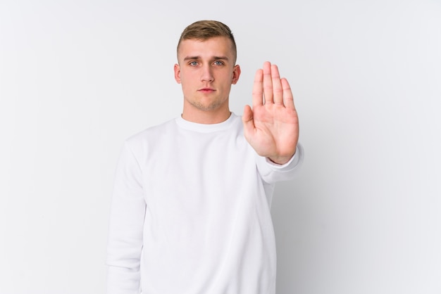 Junger kaukasischer Mann auf weißem Stehen mit ausgestreckter Hand, die Stoppschild zeigt, das Sie verhindert.