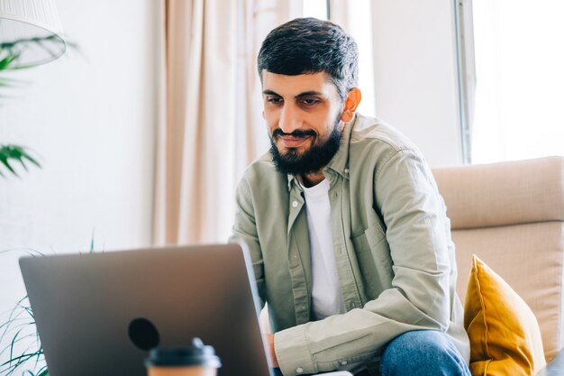 Foto junger kaukasischer mann college-student, der mit laptop entfernt zu hause mit videoanruf studiert, weben. fernbildungskonzept.