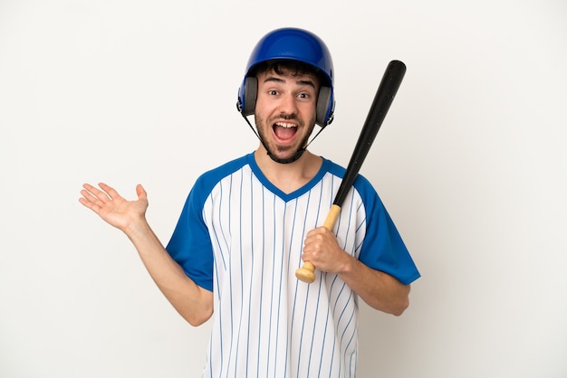 Junger kaukasischer Mann, der Baseball isoliert auf weißem Hintergrund mit schockiertem Gesichtsausdruck spielt