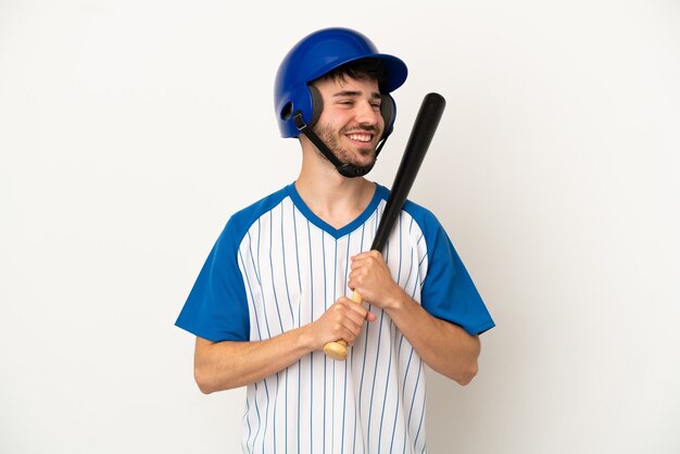 Junger kaukasischer Mann, der Baseball spielt, isoliert auf weißem Hintergrund, der mit den Armen an der Hüfte posiert und lächelt