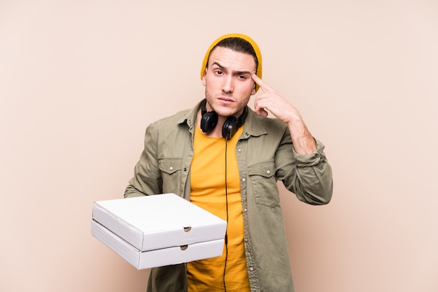 Junger kaukasischer Mann, der die Pizzas zeigen eine Enttäuschungsgeste mit dem Zeigefinger hält.