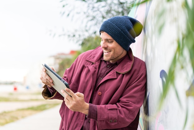 Junger kaukasischer mann, der draußen eine tablette hält