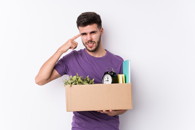 Junger kaukasischer Mann, der ein neues Haus lokalisiert zeigt eine Enttäuschungsgeste mit dem Zeigefinger umzieht.