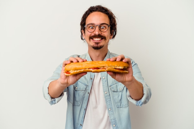 Junger kaukasischer Mann, der ein Sandwich lokalisiert auf Weiß hält