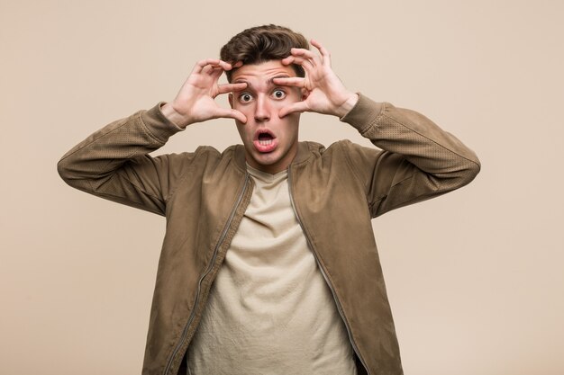 Junger kaukasischer Mann, der eine braune Jacke trägt, die Augen offen hält, um eine Erfolgschance zu finden.