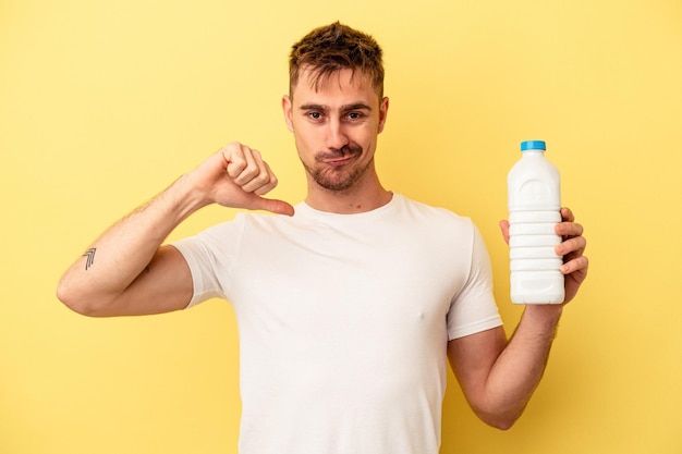 Junger kaukasischer Mann, der eine Flasche Mil auf gelbem Hintergrund hält, fühlt sich stolz und selbstbewusst, Beispiel zu folgen.