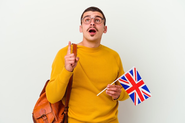 Junger kaukasischer Mann, der Englisch studiert, lokalisiert auf weißer Wand, die oben mit geöffnetem Mund zeigt.