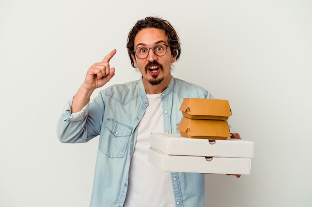 Junger kaukasischer Mann, der Hamburger eine Pizza hält, die eine Idee, Inspirationskonzept hat.