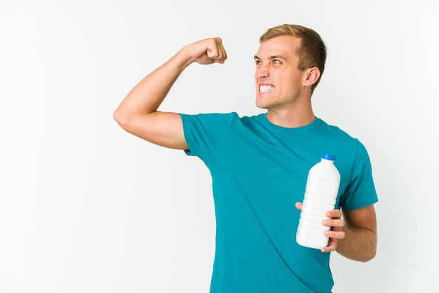 Junger kaukasischer Mann, der Milch trinkt lokalisiert auf weißem Hintergrund, der Faust nach einem Sieg, Gewinnerkonzept anhebt.