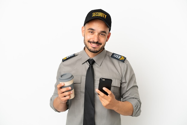Junger kaukasischer Mann der Sicherheit isoliert auf weißem Hintergrund, der Kaffee zum Mitnehmen und ein Handy hält