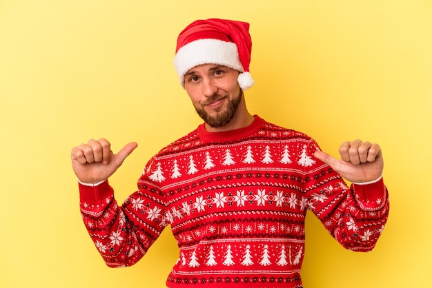 Junger kaukasischer Mann, der Weihnachten isoliert auf gelbem Hintergrund feiert, fühlt sich stolz und selbstbewusst, Beispiel zu folgen.