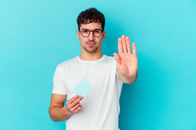 Junger kaukasischer Mann, der Weltwassertag vereinzelt stehend mit ausgestreckter Hand feiert, die Stoppschild zeigt, das Sie verhindert.