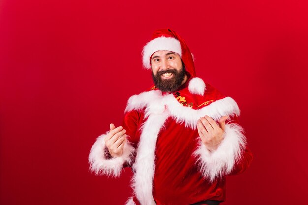 Junger kaukasischer mann des brasilianischen weihnachtsmanns, der mit den händen anruft und mit den händen einlädt