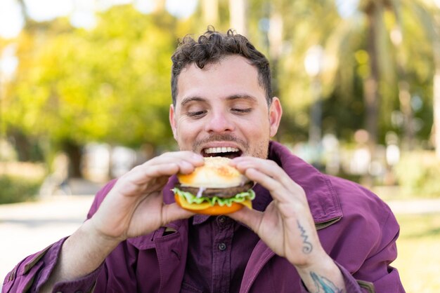 Junger kaukasischer Mann im Freien mit einem Burger