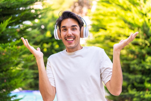 Junger kaukasischer Mann in einem Park überraschte und hörte Musik