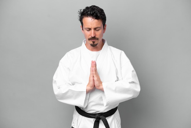 Foto junger kaukasischer mann isoliert auf grauem hintergrund, der karate macht und grüßt