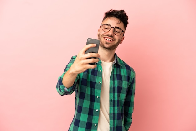 Junger kaukasischer Mann isoliert auf rosa Hintergrund, der ein Selfie macht