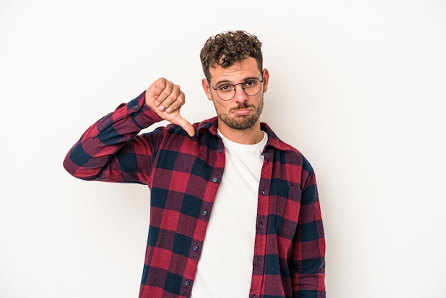 Foto junger kaukasischer mann isoliert auf weißem hintergrund, der eine abneigungsgeste zeigt, daumen nach unten. meinungsverschiedenheit konzept.