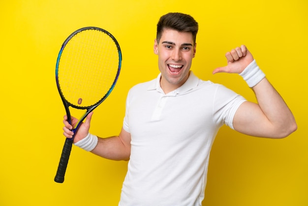 Junger kaukasischer Mann lokalisiert auf weißem Hintergrund, der Tennis spielt und stolz auf sich selbst ist